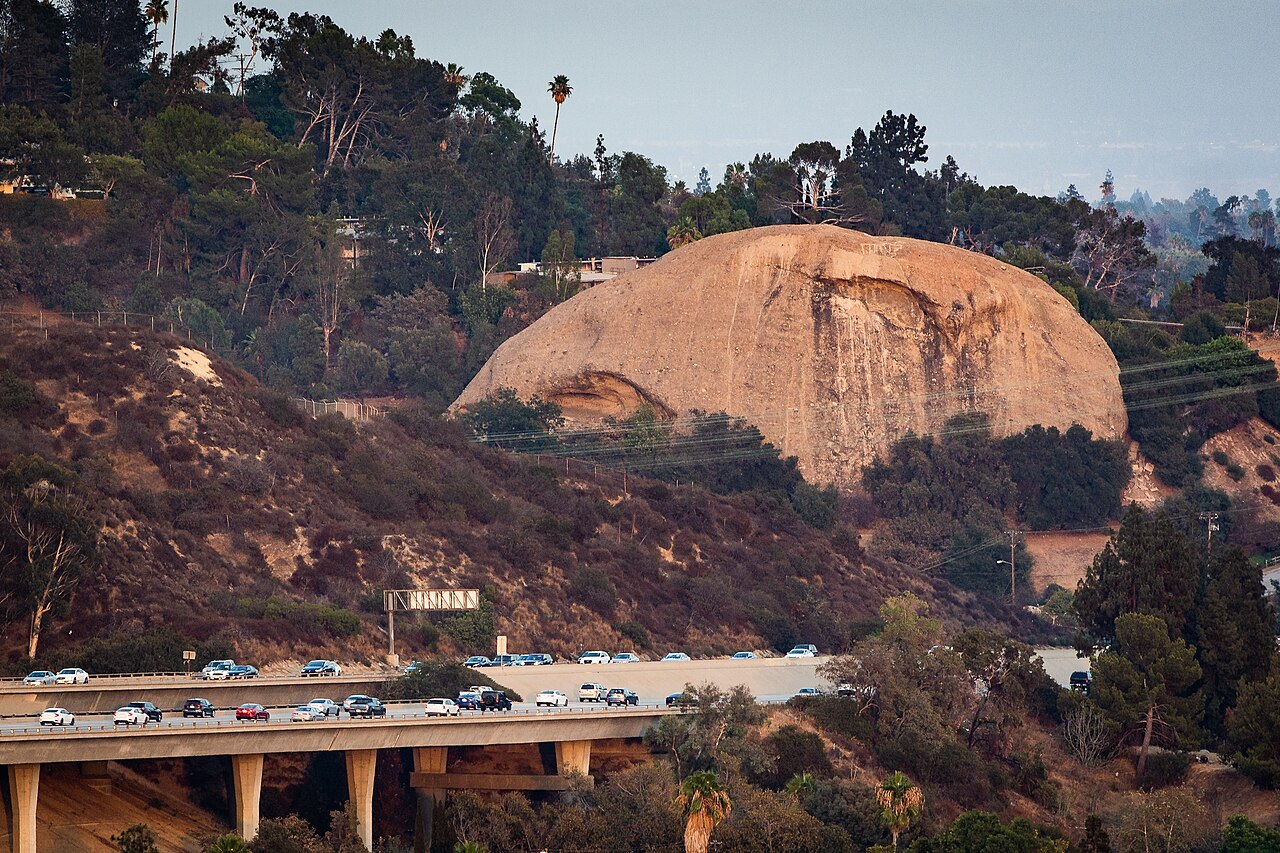 Eagle Rock landform illuminated at dusk, with surrounding hillside homes and freeway.