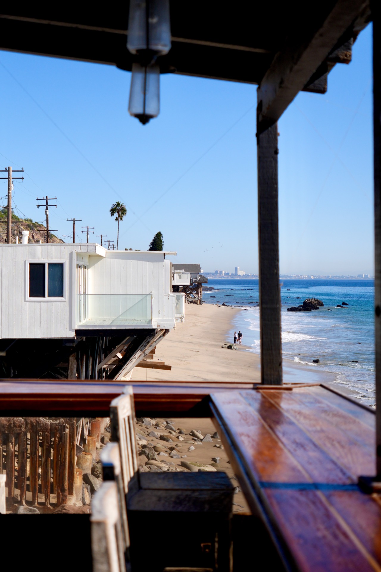 Stilt houses along Malibu beach with Santa Monica Bay skyline in the distance, California.